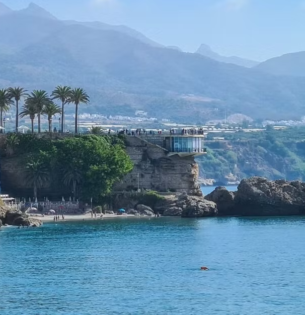 Solnedgång över Balcón de Europa i Nerja med vita hus, palmer och turkost hav